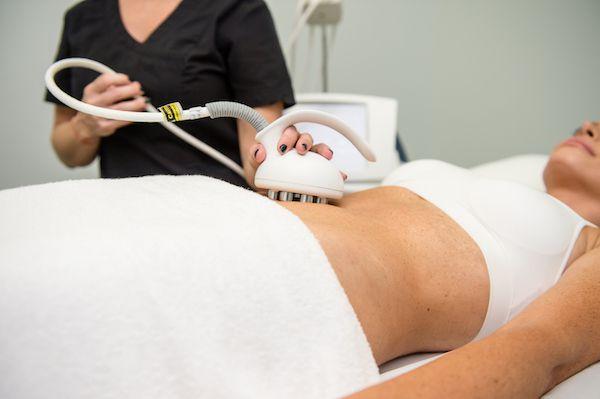 Practitioner moving a radiofrequency applicator over a woman's abdomen